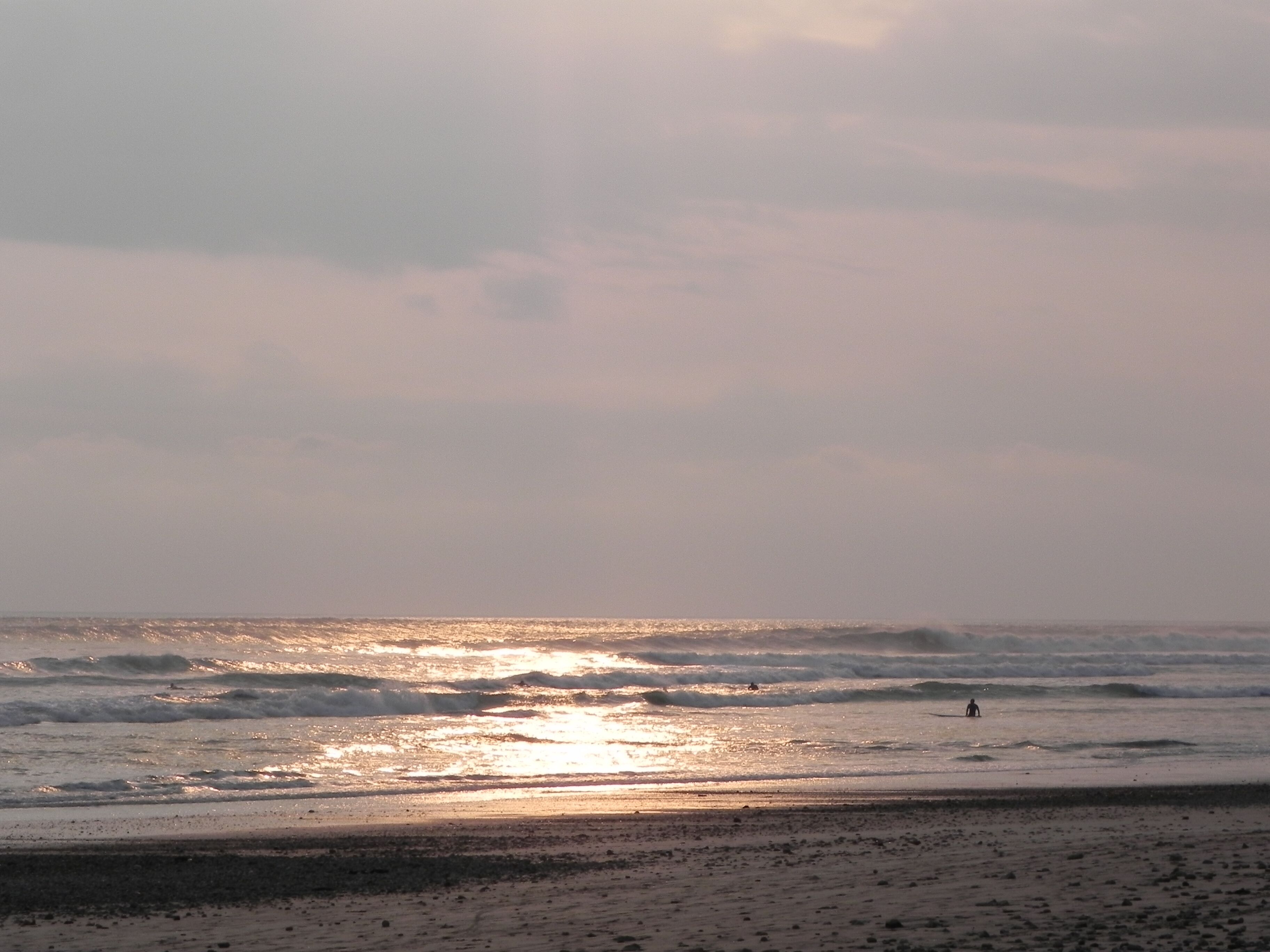 A beach with waves and a person in the distance.