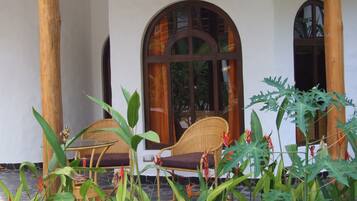 Un espacio al aire libre cubierto con mobiliario de mimbre y plantas tropicales.