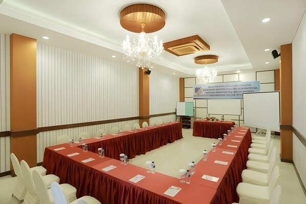A conference room with a long table, white chairs, and a whiteboard. - Sutan Raja Hotel & Convention Palu (Palu)