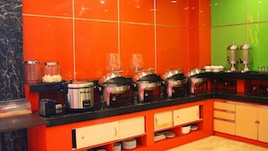A kitchen with red cabinets, a black countertop, and various cooking appliances. - Maleosan Inn Manado (Manado)