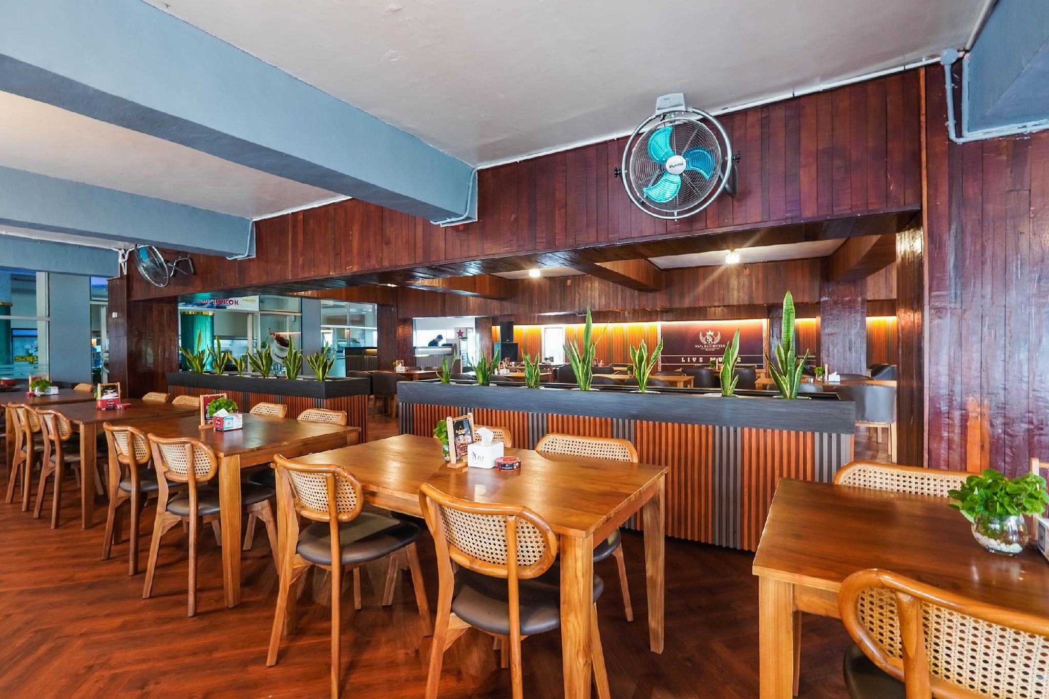 A restaurant with wooden furniture, a counter, and a fan.