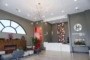 A modern hotel lobby with a reception desk, seating area, and a large window. - Hartford Hotel, BW Signature Collection (Rosemead)
