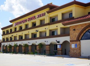 A hotel with a yellow facade, multiple balconies, and a large arched entrance. - Hartford Hotel, BW Signature Collection (Rosemead)