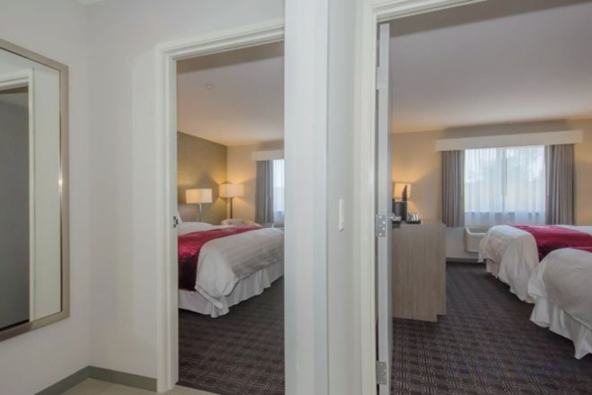 A hotel room with two beds, a desk, and a window.
