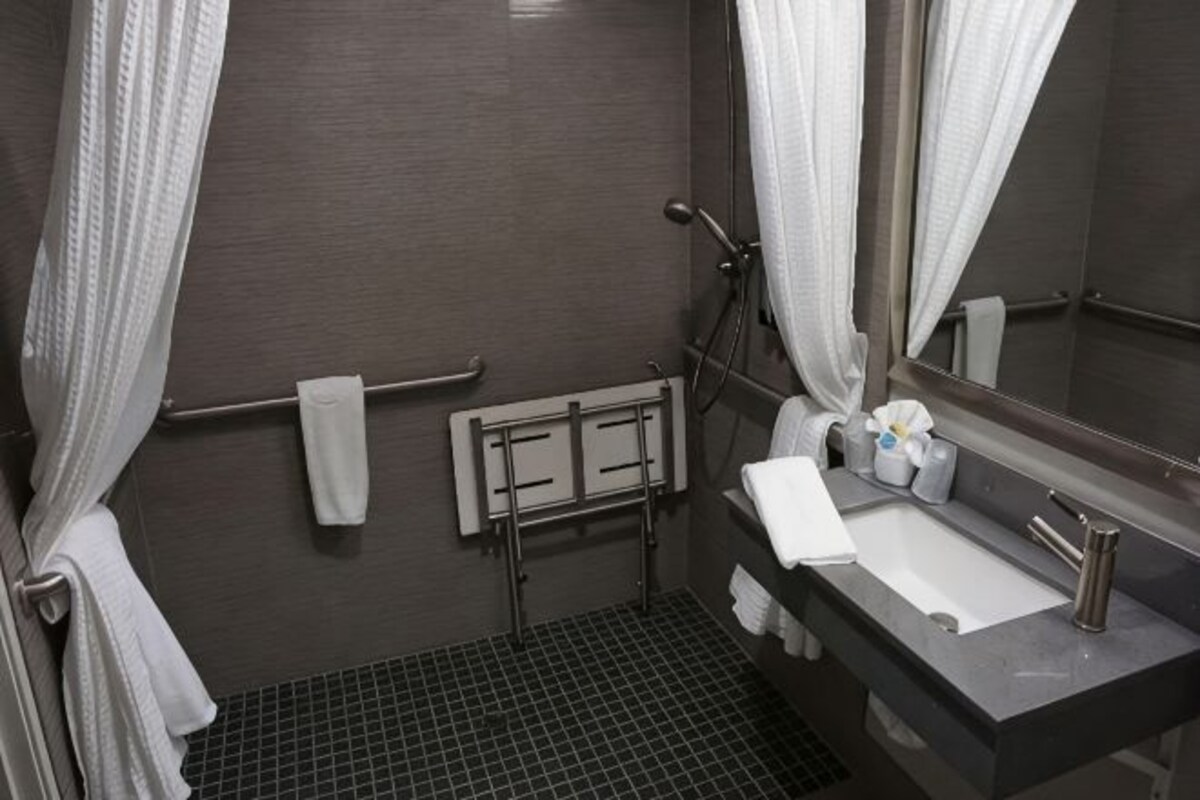 A bathroom with a shower, a sink, a towel rack, and a mirror.