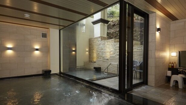 A modern spa area with a glass enclosure, stone wall, and a small seating area. - Hotel de Yama, Hakone Lake Side (Hakone)