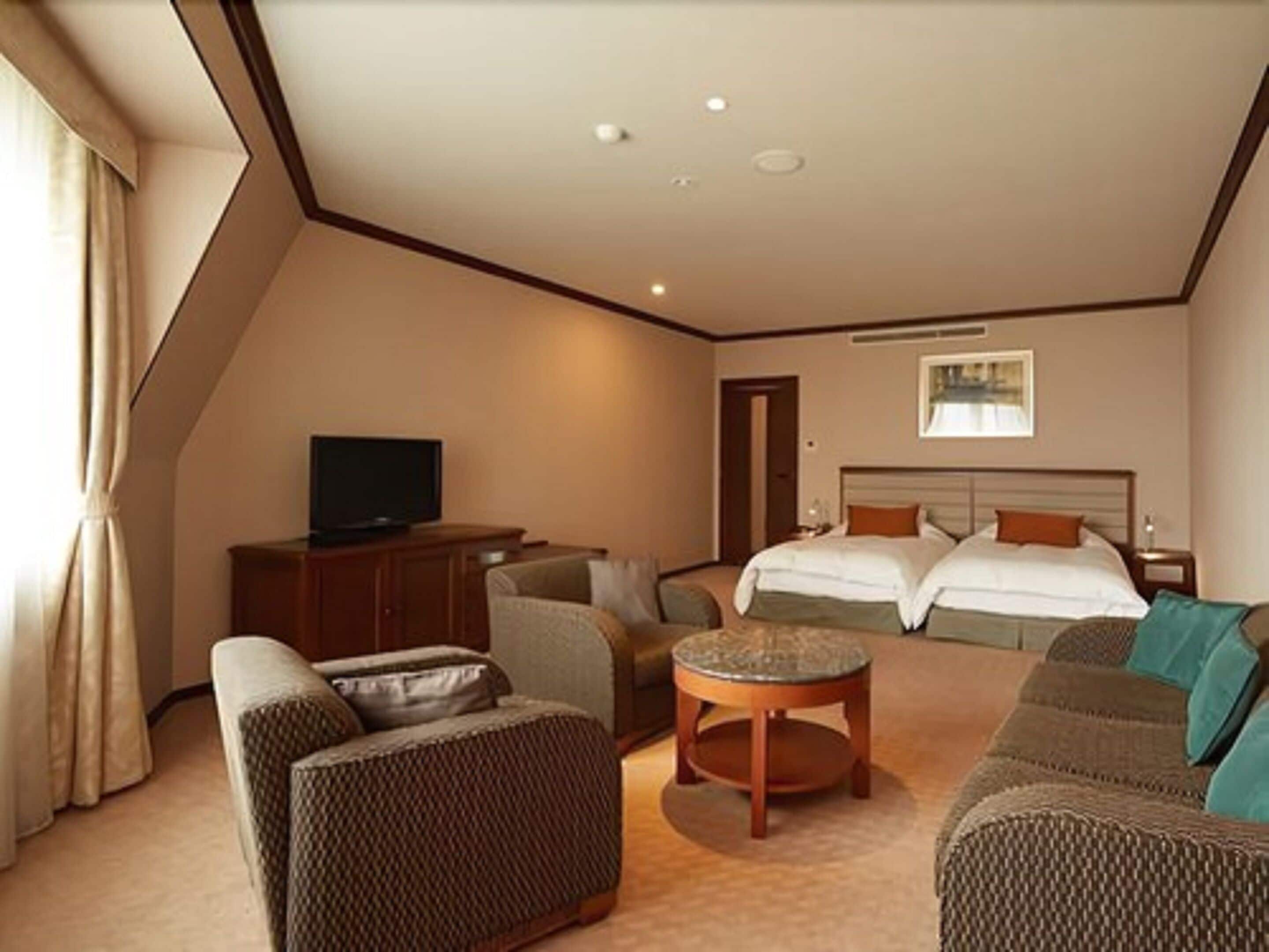 Habitación de hotel con cama, sofá, televisión y una mesita.