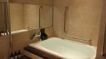 A modern bathroom with a bathtub, a glass shower enclosure, and a vanity with toiletries.