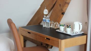 Una pequeña mesa de madera con tapa negra, una silla de cuero marrón y un hervidor blanco.