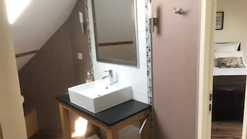 Un bagno con un lavandino bianco, uno specchio e un mobile contenitore in legno.