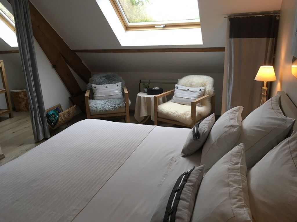 Ein Schlafzimmer mit einem großen Bett, zwei Stühlen, einem kleinen Tisch und einem Oberlicht.