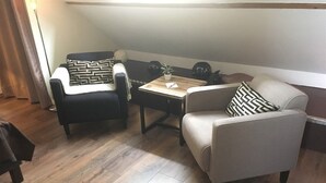 A cozy living room with a sofa, armchair, and a small table with a plant. - Au Coeur Des Hôtes (Steenvoorde)