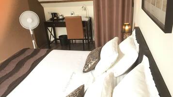 Una habitación de hotel con cama, escritorio, silla, lámpara y un cuadro en la pared.