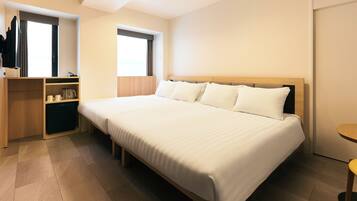 Habitación de hotel con una cama grande, un armario de madera, una mesita pequeña y una ventana con cortinas.
