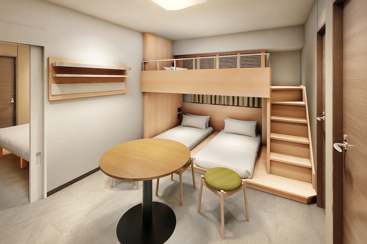 Ein Stockbett mit Schreibtisch und Stuhl, ein kleiner Tisch und eine Tür.