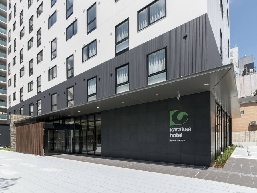 A modern hotel building with a prominent entrance, large windows, and a visible logo.