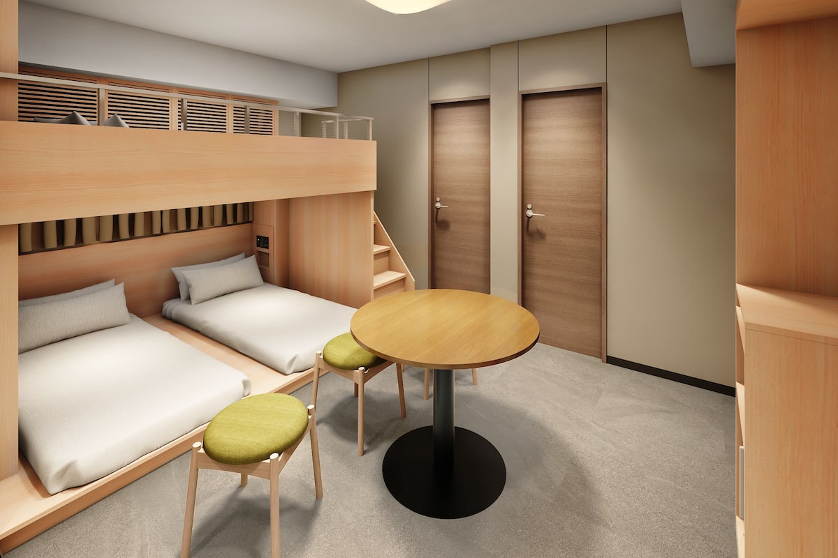 Ein kleines Zimmer mit Etagenbetten, einem kleinen Tisch und einem Stuhl.
