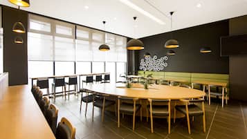A conference room with a long table, chairs, and pendant lighting.