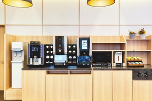 A modern hotel kitchen with a coffee machine, microwave, and hot water dispenser.