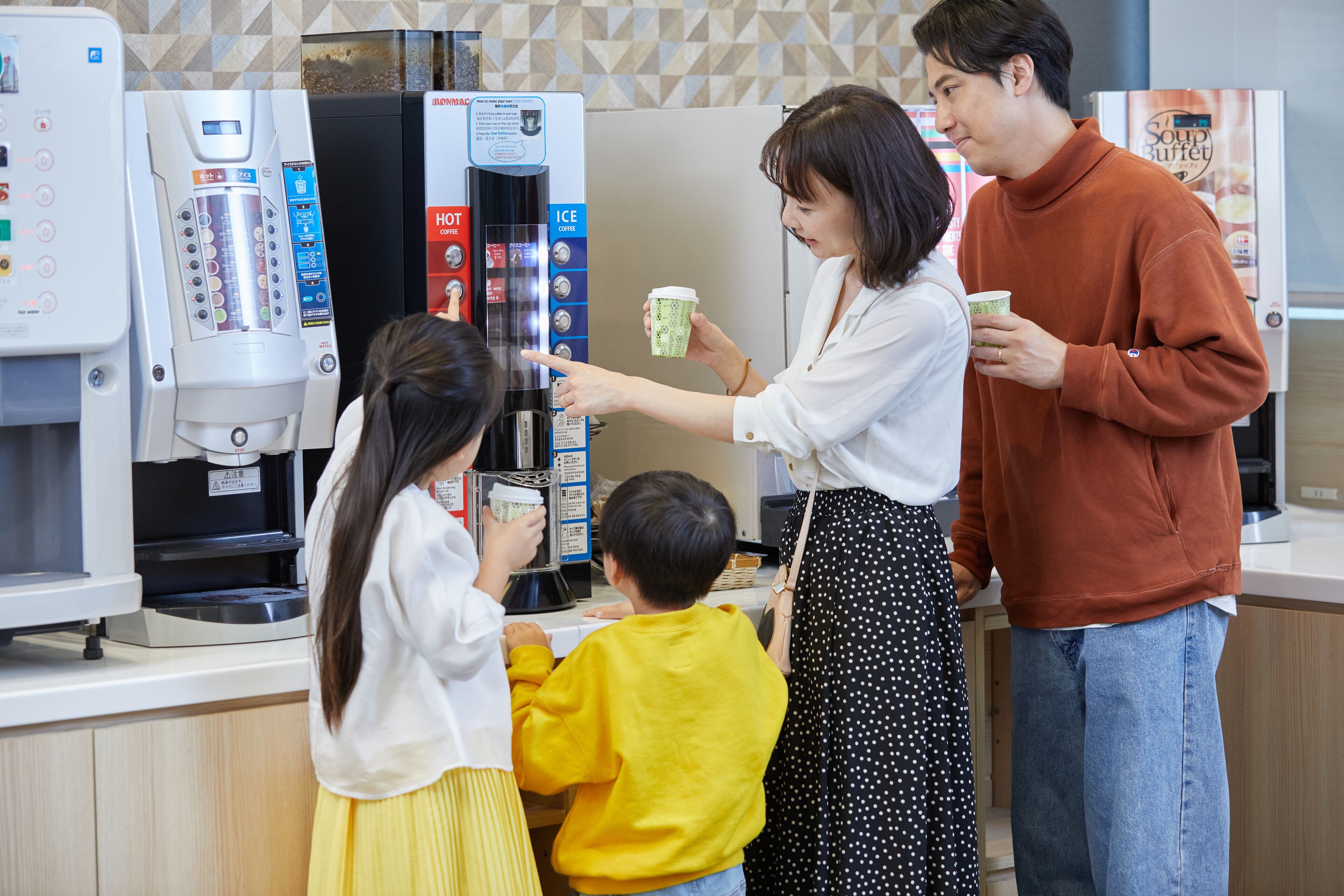 Una famiglia interagisce con una macchina da caffè in un ambiente moderno.