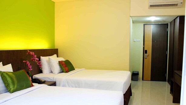 A hotel room with two beds, a green wall, and a wooden headboard. - Bali De Anyer Hotel and Restaurant (Carita)
