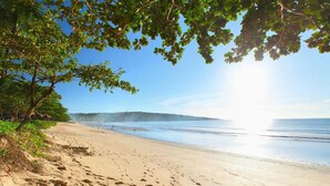 A beach with footprints, a clear sky, and trees. - Bali De Anyer Hotel and Restaurant (Carita)