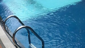 A swimming pool with clear blue water and a metal ladder leading into it. - Bali De Anyer Hotel and Restaurant (Carita)