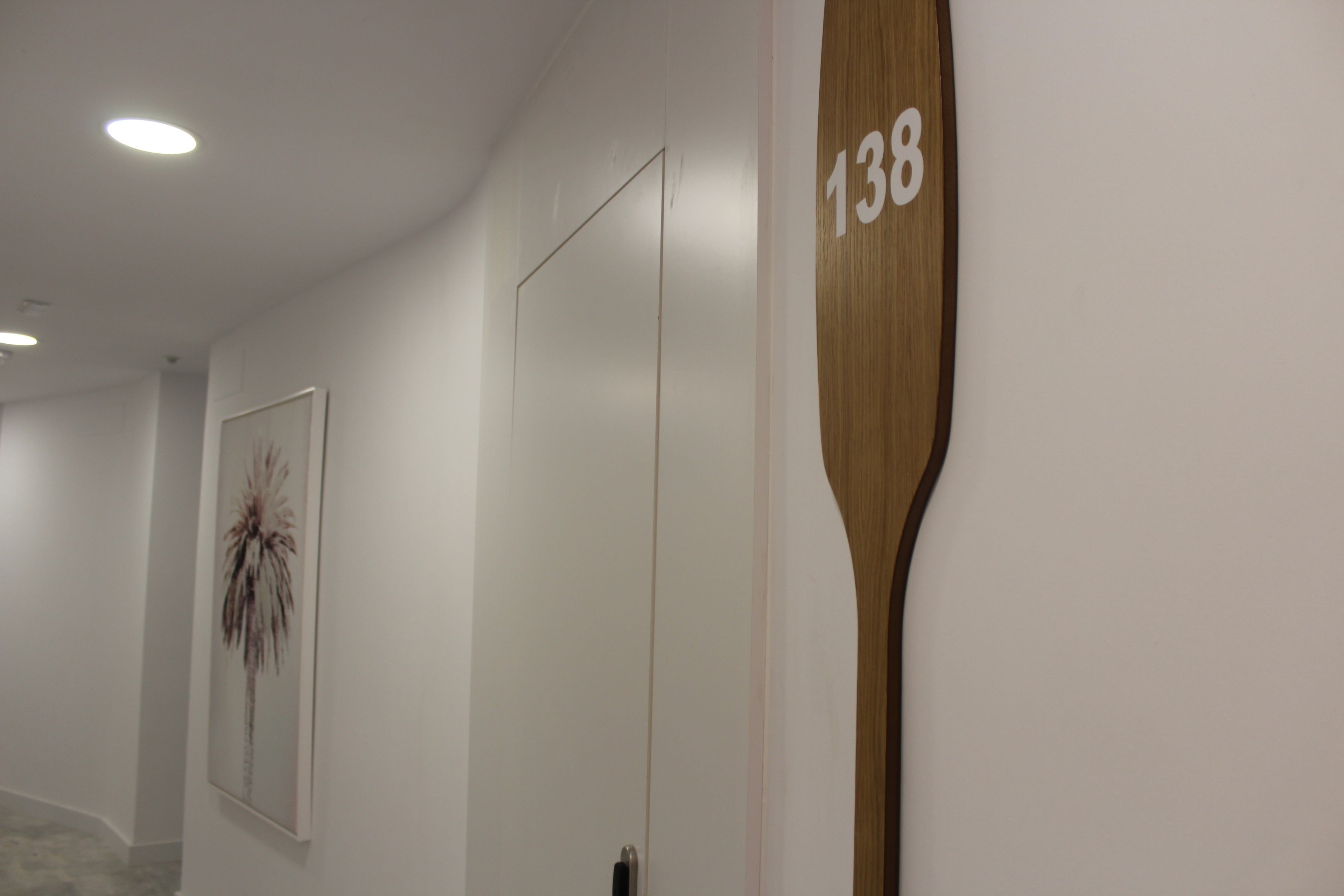 Un corridoio con un cartello numerico in legno, un quadro incorniciato e una porta.