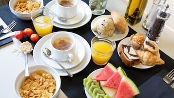 Desayuno con cereal, café, jugo, croissants y rebanadas de sandía.