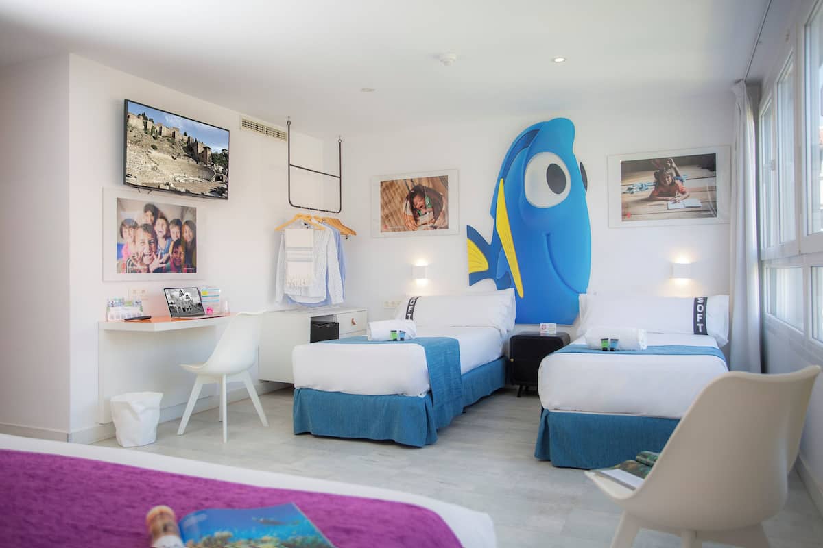 Een moderne hotelkamer met een bed, twee nachtkastjes, een bureau, een stoel en een grote visdecoratie.