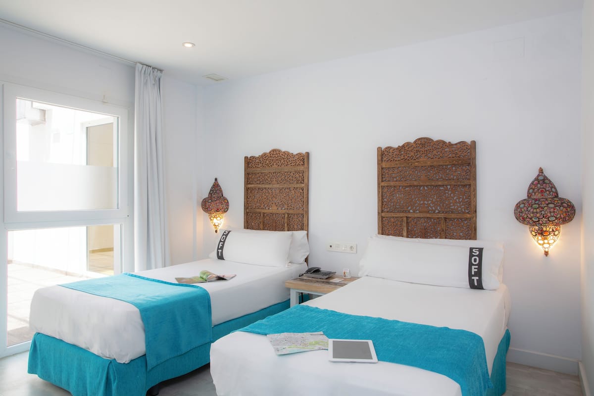 Een hotelkamer met twee bedden, een bureau en een laptop.