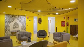 Un hall d’entrée aux couleurs jaune, doté de meubles modernes, d’un mur décoratif et d’une structure en forme de filet suspendu.