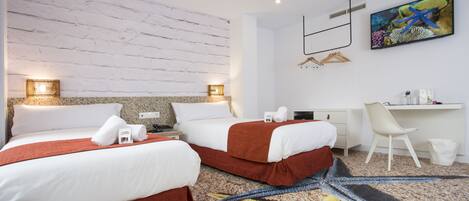 A hotel room with two beds, a desk, a chair, and a painting of an underwater scene.