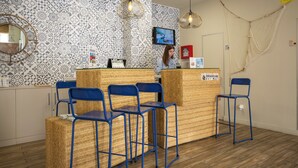 Un espace d’accueil avec un mur décoré de motifs, un téléviseur et un comptoir de réception.