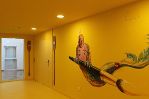 A hallway with a mural of a mermaid and a wooden paddle on the wall.