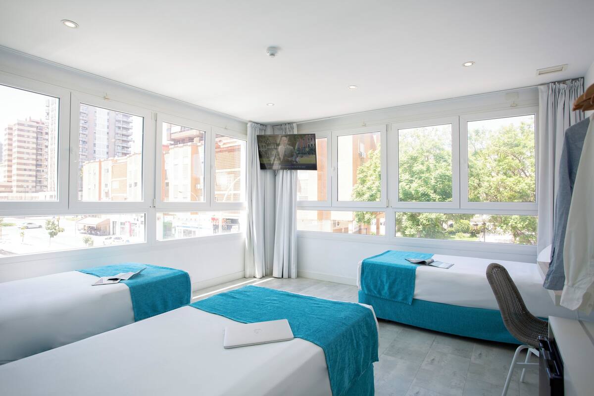 Een hotelkamer met twee bedden, een bureau, een stoel en een televisie.