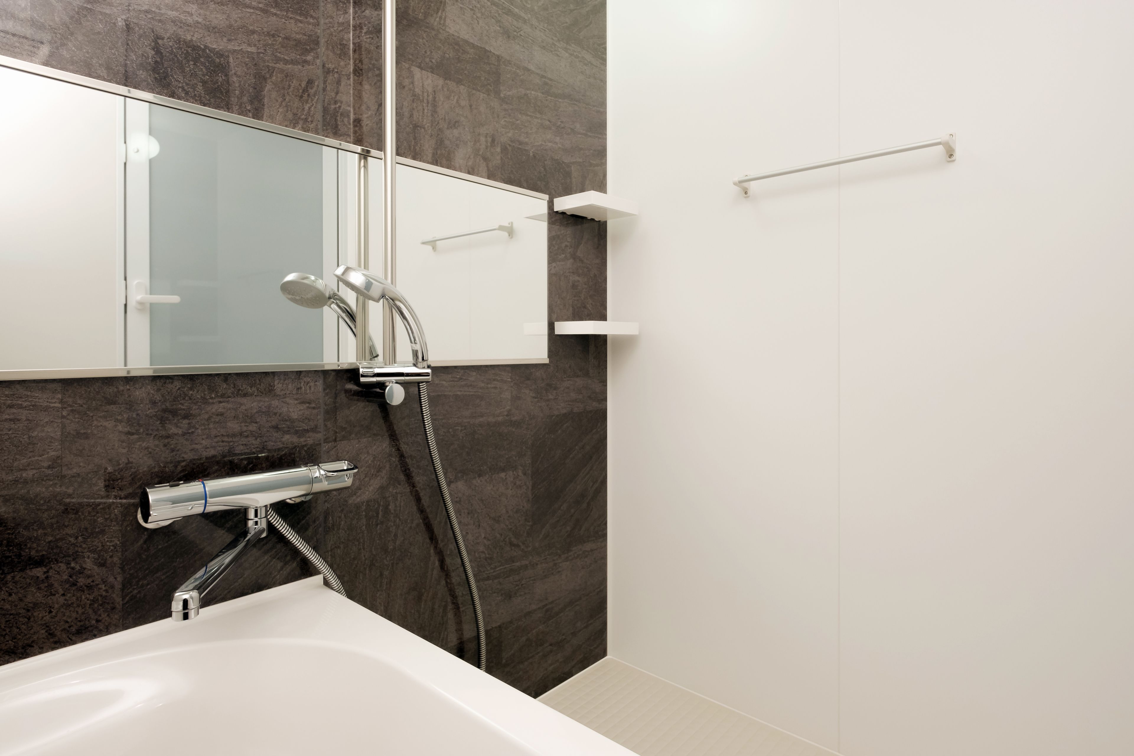 A modern bathroom with a bathtub, a glass-enclosed shower, and a marble wall.
