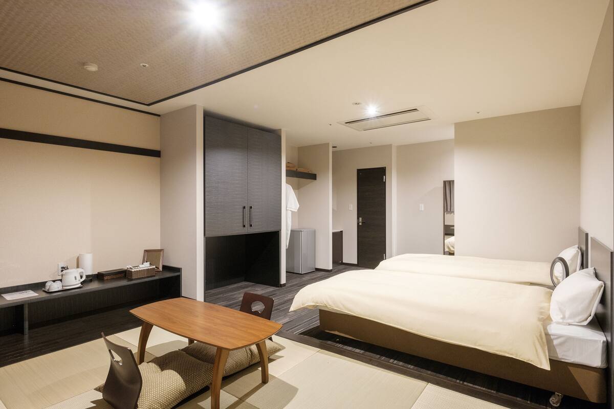 A hotel room with a bed, a desk, a chair, and a small table.