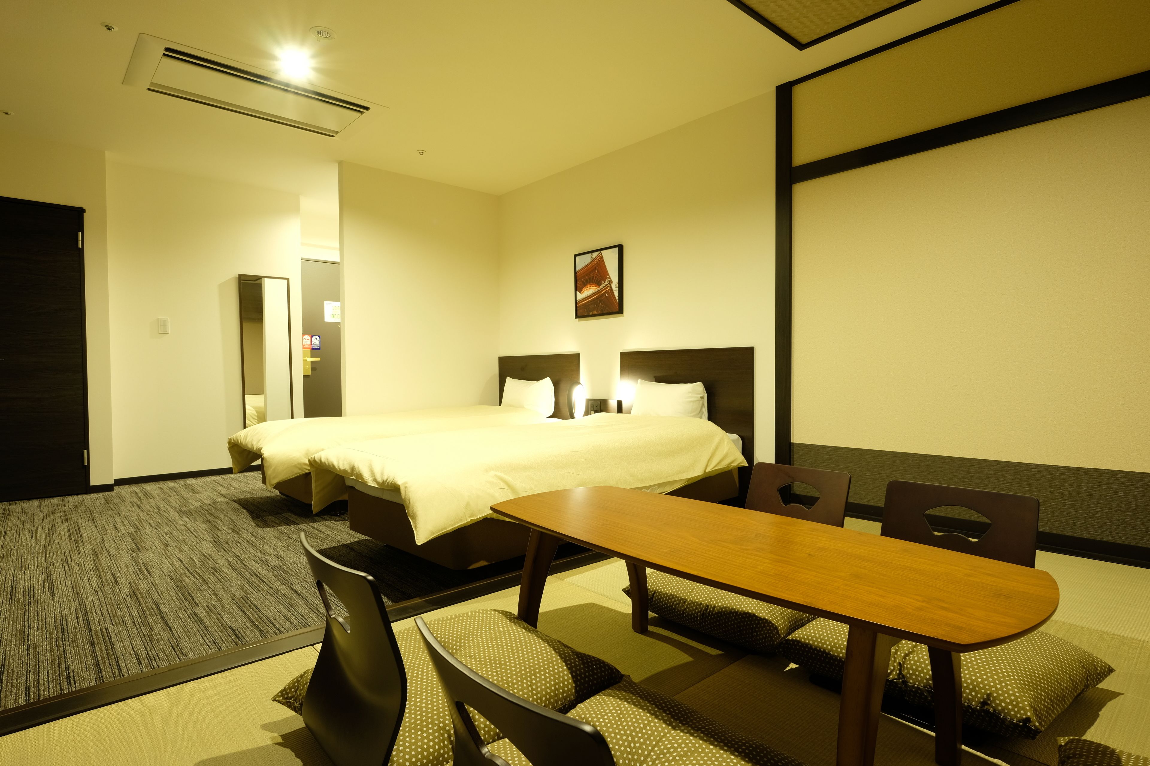 A hotel room with a bed, a dining table with chairs, and a carpeted floor.