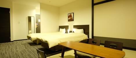A hotel room with a bed, a dining table with chairs, and a carpeted floor.
