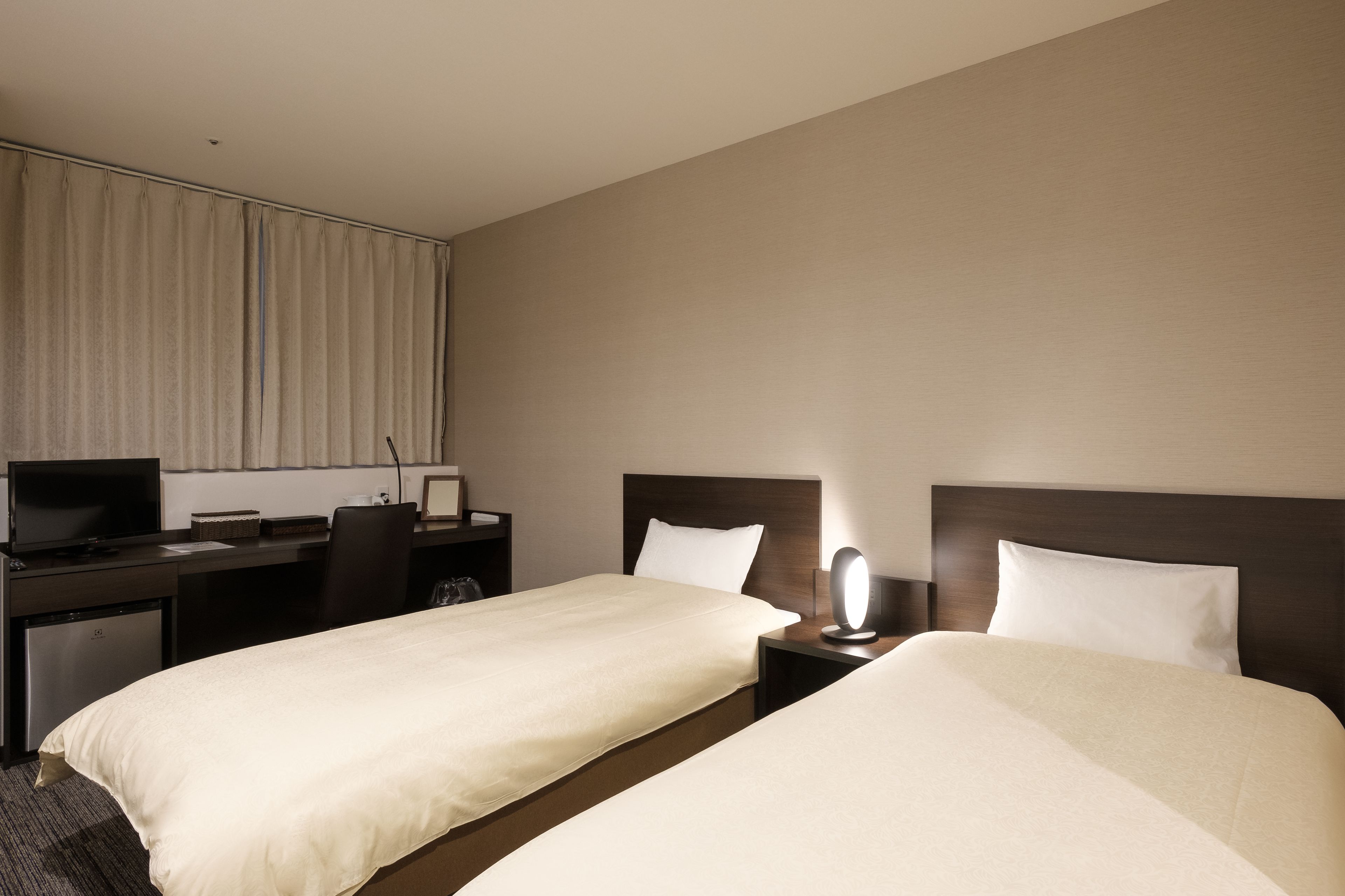 Habitación de hotel con dos camas, un escritorio, un televisor y un espejo.
