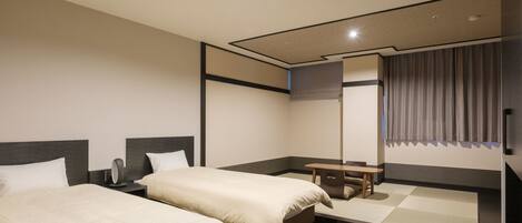 A hotel room with two beds, a small table, and a mirror.