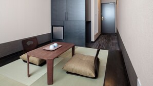 A modern hotel room with a wooden dining table, two chairs, a small refrigerator, and a traditional Japanese-style sofa. - The Premium Hotel in Rinku (Izumisano)