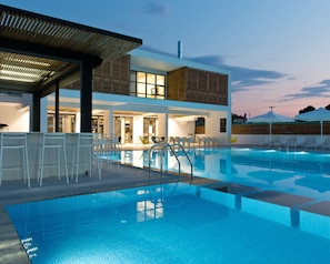 A modern hotel with a swimming pool, outdoor seating, and a covered area. - The OAK Hotel Keramoti (Nestos)