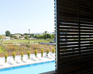 A view of a swimming pool with lounge chairs and a fenced area with trees. - The OAK Hotel Keramoti (Nestos)