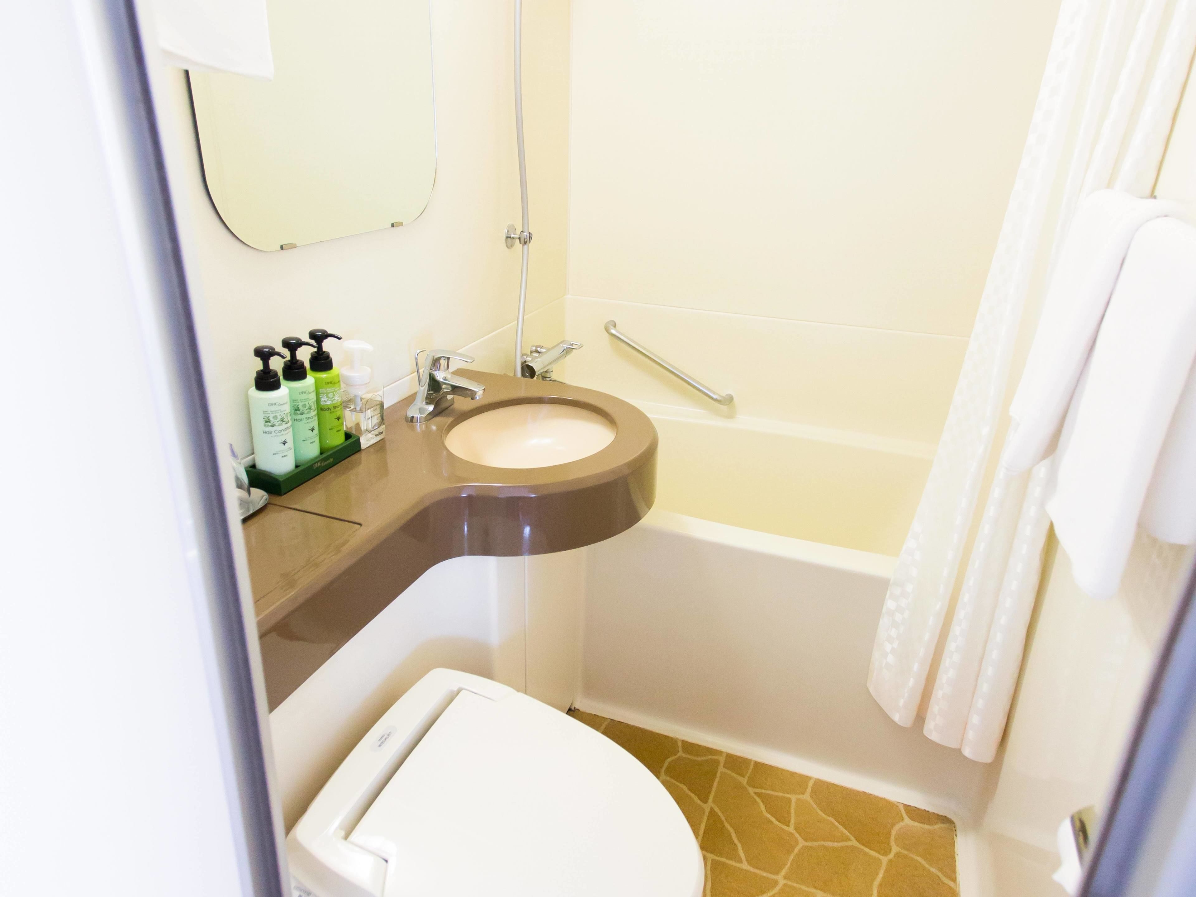 A bathroom with a sink, mirror, toiletries, and a bathtub.