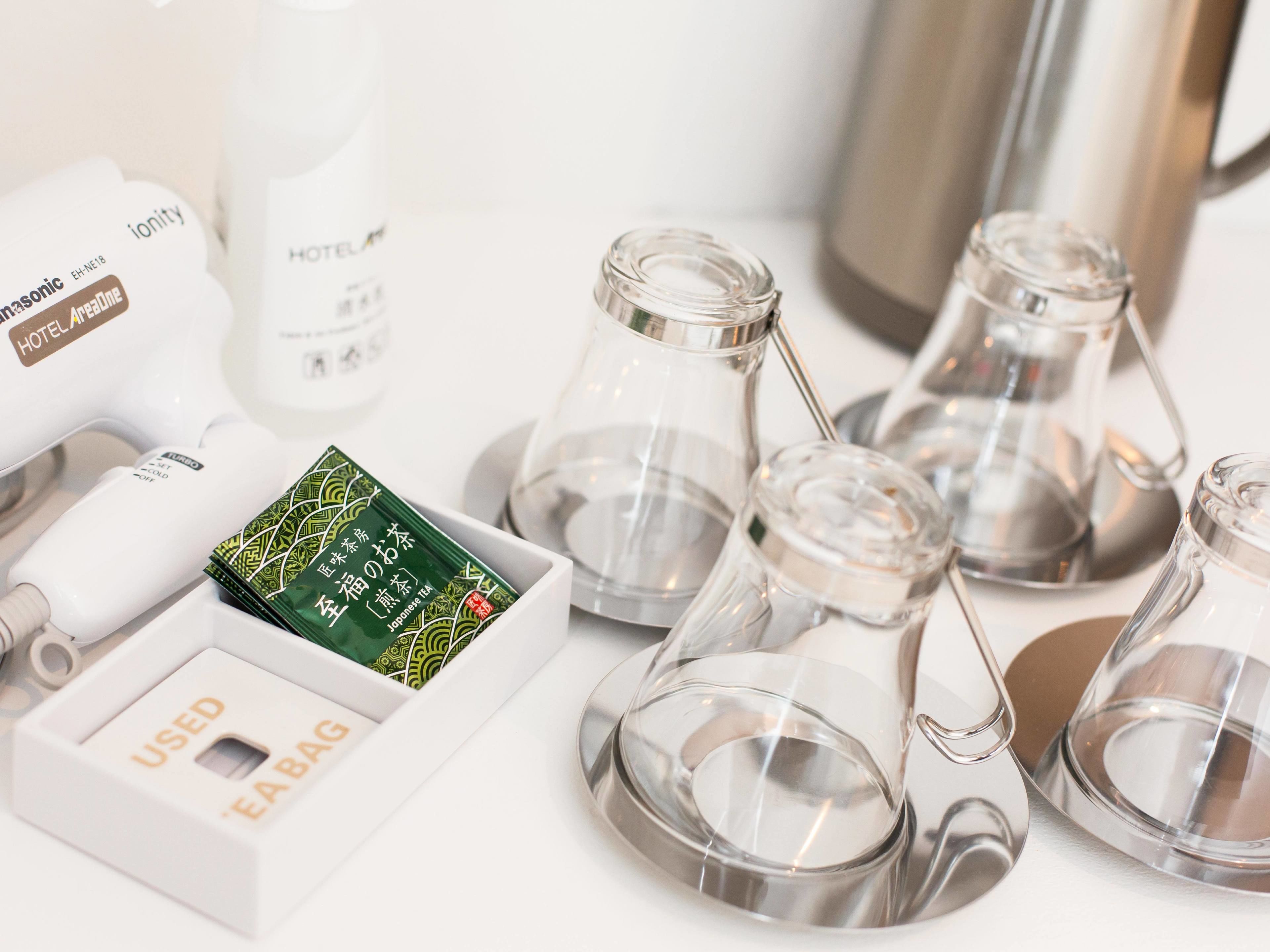A hotel minibar with a Panasonic phone, a bottle of Japanese tea, and several glass carafes.