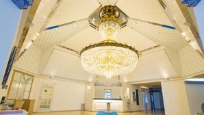 A spacious lobby with a large chandelier, a blue carpet leading to the reception desk, and a high ceiling with a geometric pattern. - HOTEL AreaOne SAKAIMINATO MARINA (Sakaiminato)