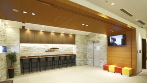 Een moderne receptie met een stenen muur, houten plafond en een wandgemonteerde flatscreen-tv.