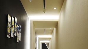 Een gang met houten vloer, een zwarte muur met kunst en een lichtgekleurde muur.